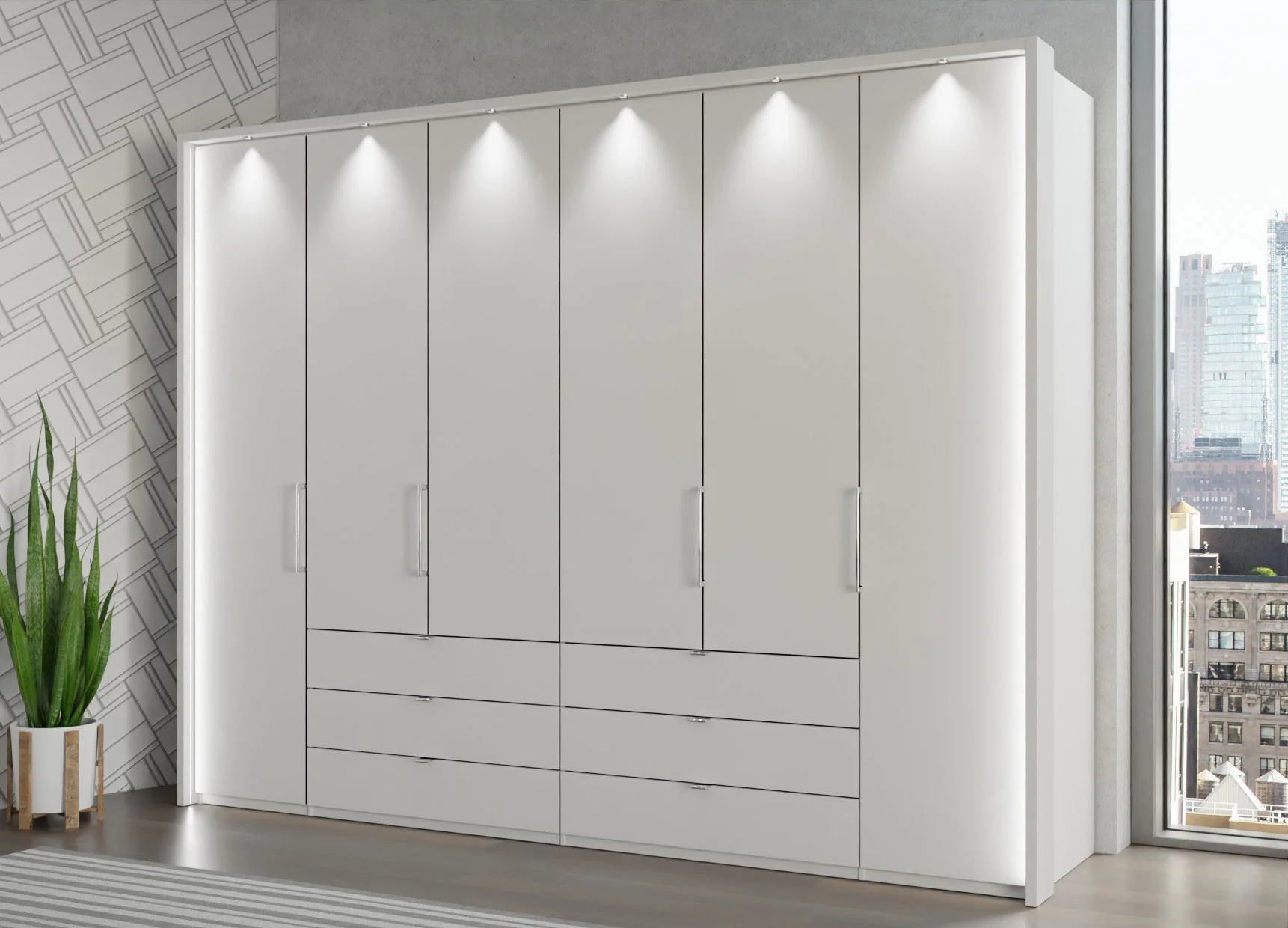 A large Wiemann modern 300cm bi-folding wardrobe with drawers features eight doors and six drawers, illuminated by spotlights above. It stands against a wall near a tall green plant and a window showing a cityscape outside. Quality wardrobe UK.